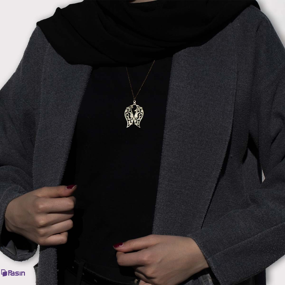 گردن‌آویز برنجی طرح اسلیمی بادامی در موقعیت کاربرد همراه با مدل که در فضای بین، طرح نبودن یک ماهی را نمایش داداه است.